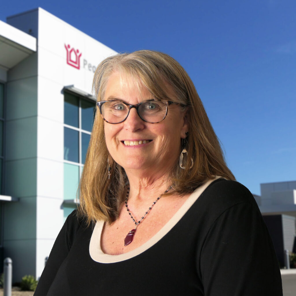 Woman wearing glasses smiling at camera.