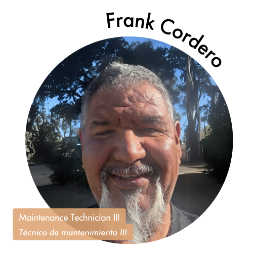 Pictured is a circle shaped image of Frank Cordero. Frank is smiling with a grey beard and trees in the background short hair and greenery in the background. His name is on the upper right in bold black letters curving around the image. On the bottom left, his position title is written in white text and highlighted in a medium tan color. His position title is, "Maintenance Technician III, Técnico de mantenimiento III"